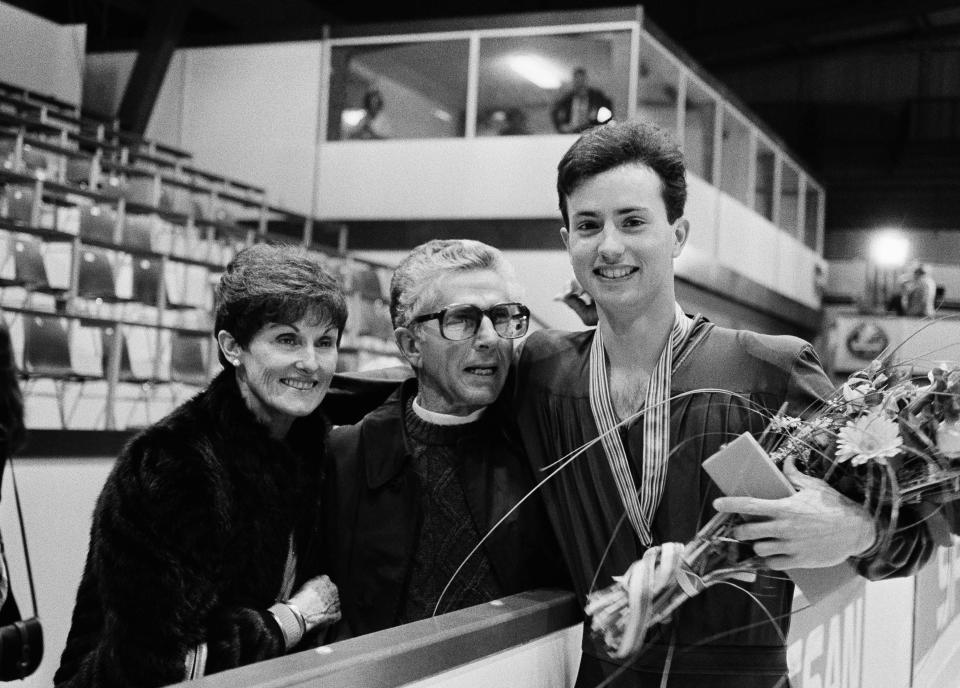 FILE - Brian Boitano stands with flowers and gold medals with his parents in the Geneva ice stadium, March 21, 1986, after he won the world champion title and the medal for the best performance of the men's singles at the World Figure Skating Championships. Boitano, an Olympic gold medalist, a two-time world champion and the winner of four national titles, also has a flair for food and bringing people together. Boitano’s Lounge opened in 2019 in Lincoln, Neb., and the Hall of Fame skater brought the experience to the SAP Center for a special activation during the U.S. Figure Skating Championships in January 2023. (AP Photo/Michel Lipchitz, File)