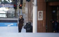 A hostage runs towards a police officer outside Lindt cafe, where other hostages are being held, in Martin Place in central Sydney December 15, 2014. REUTERS/Jason Reed