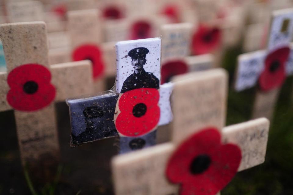 A black and white photograph of a member of the military on one of the memorial crosses on display at the Field of Remembrance ahead of a service at Westminster Abbey in London (PA Wire)