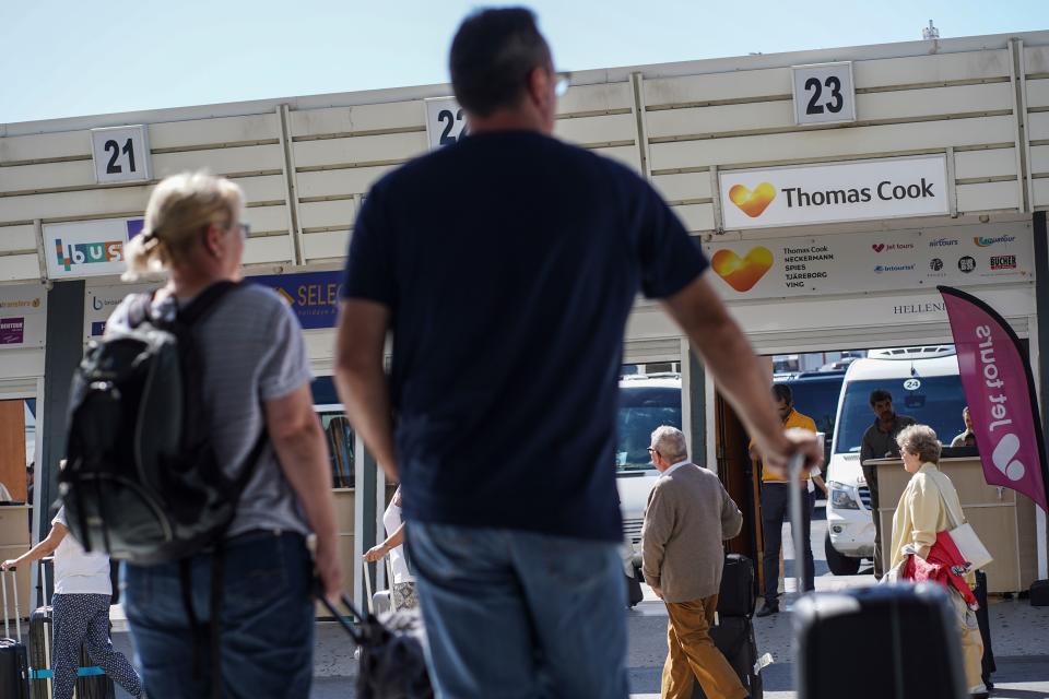 Tourists stand by a counter of Thomas Cook at Heraklion airport on the island of Crete after the travel group collapsed