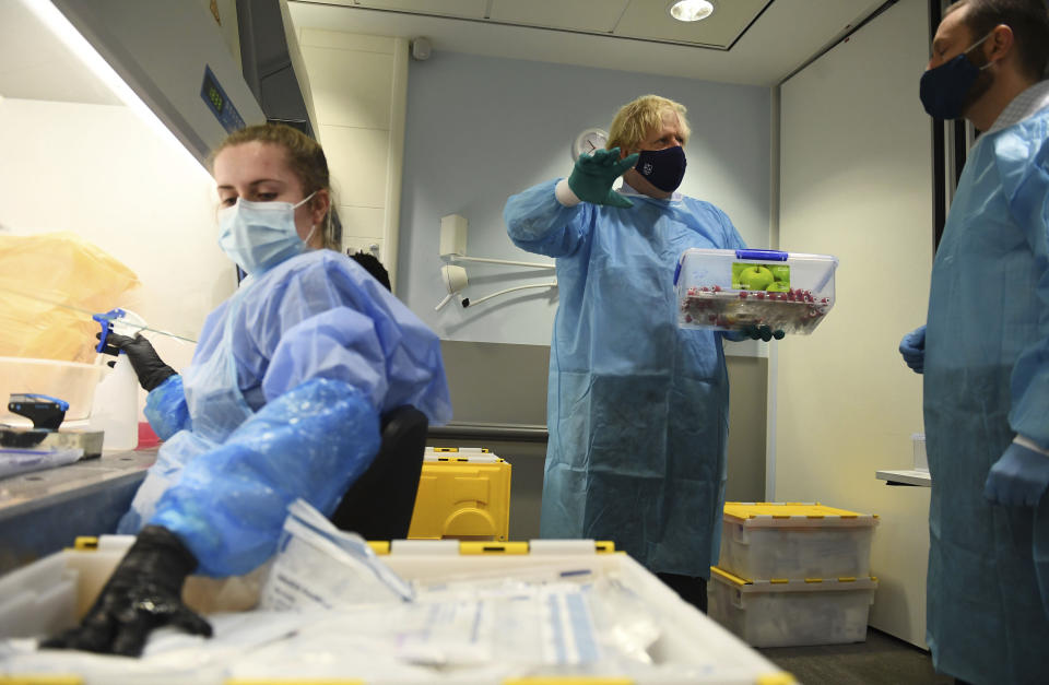 Britain's Prime Minister Boris Johnson, centre, tours the Lighthouse Laboratory, used for processing polymerase chain reaction (PCR) samples for coronavirus, during a visit to the Queen Elizabeth University Hospital campus in Glasgow on his one day visit to Scotland, Thursday, Jan. 28, 2021. Johnson is facing accusations that he is not abiding by lockdown rules as he makes a trip to Scotland on Thursday to laud the rapid rollout of coronavirus vaccines across the United Kingdom. (Jeff Mitchell/Pool Photo via AP)