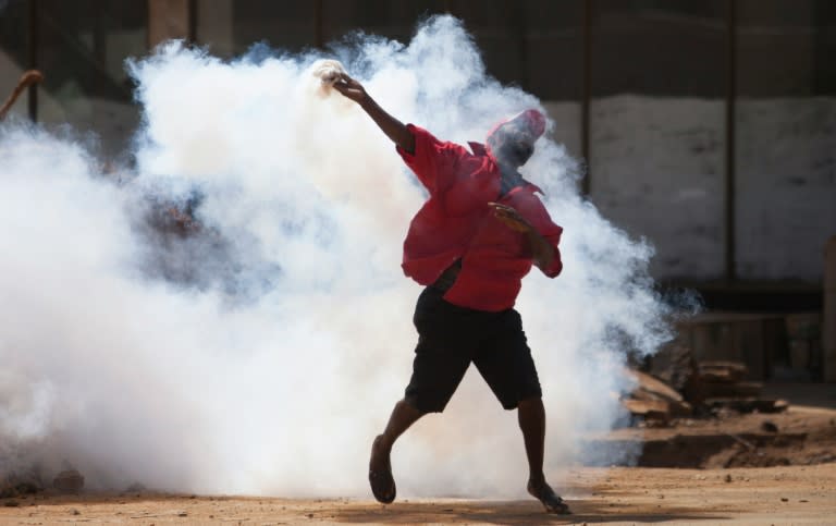 A supporter of the Zimbabwe opposition party Movement for Democratic Change Tsvangirai faction (MDC-T) throws back a tear gas canister during clashes with police in Harare on August 24, 2016