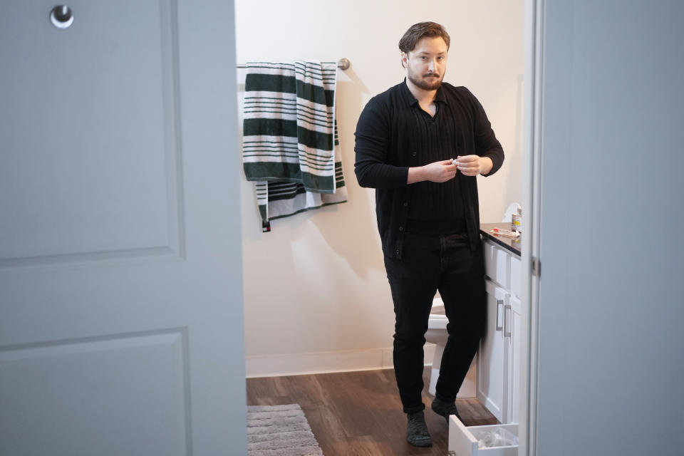 Ashton Colby holds a vial of Testosterone Cypionate Injection in his apartment bathroom in Columbus, Ohio, on Thursday, Jan. 18, 2024. Ohio Gov. Mike DeWine announced proposals this month that transgender advocates say could block access to gender-affirming care provided by independent clinics and general practitioners, leaving thousands of adults scrambling for treatment and facing health risks. Colby, 31, fears the clinic where he gets the testosterone he has taken since age 19 would no longer offer it. (AP Photo/Carolyn Kaster)