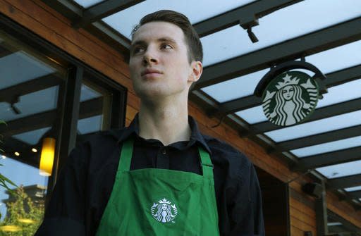 Starbucks barista Oliver Savage poses for a photo in front of a Starbucks store near where he works Monday, Aug. 29, 2016, in Seattle. Savage is joining other workers and city leaders in pushing for new