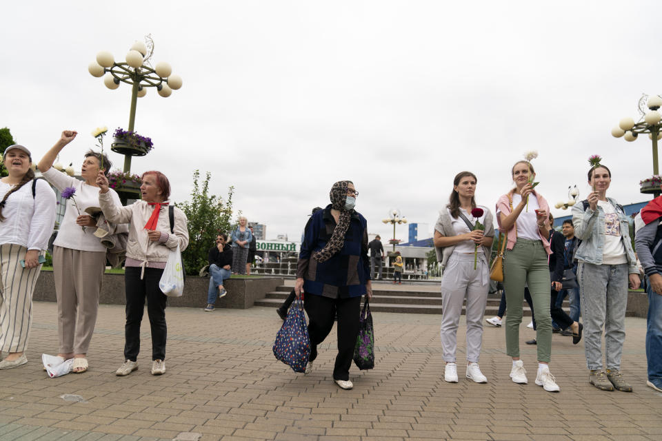 A woman walks past a protest in Minsk, Belarus, Saturday, Aug. 22, 2020. Demonstrators are taking to the streets of the Belarusian capital and other cities, keeping up their push for the resignation of the nation's authoritarian leader. President Alexander Lukashenko has extended his 26-year rule in a vote the opposition saw as rigged. (AP Photo/Evgeniy Maloletka)