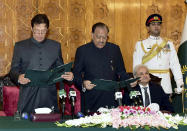 In this photo released by Pakistan's Press Information Department, Pakistani President Mamnoon Hussain, center, administers oath to newly-elected Prime Minister Imran Khan, left, at Presidential Palace in Islamabad, Pakistan, Saturday, Aug. 18, 2018. Pakistan's cricket star-turned-politician Imran Khan was sworn in as prime minister on Saturday despite protests by opposition parties, which accuse the security services of intervening on his behalf in last month's elections. (Press Information Department via AP)