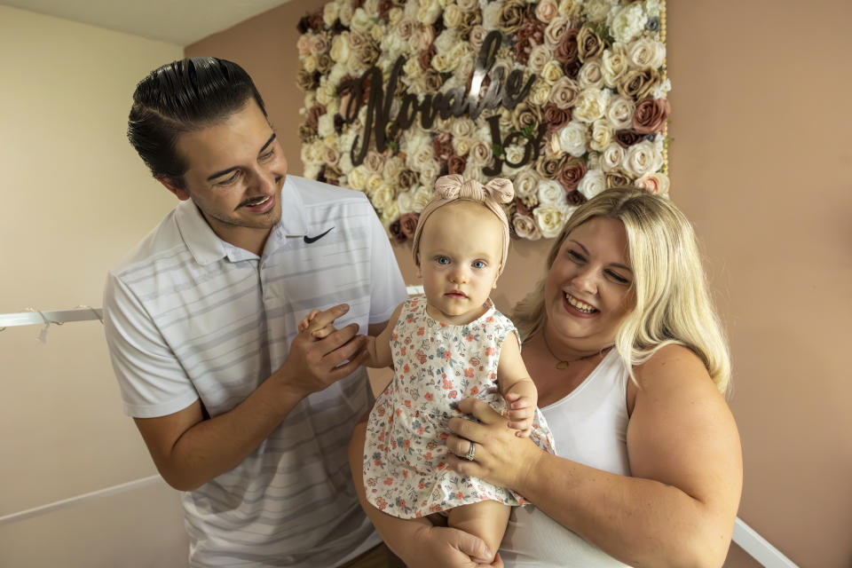 Sam Earle, left, and his wife, Tori, hold their daughter, Novalie, in her room at home Tuesday, May 7, 2024, in Lakeland, Fla. Novalie was born through an embryo adoption. (AP Photo/Mike Carlson)