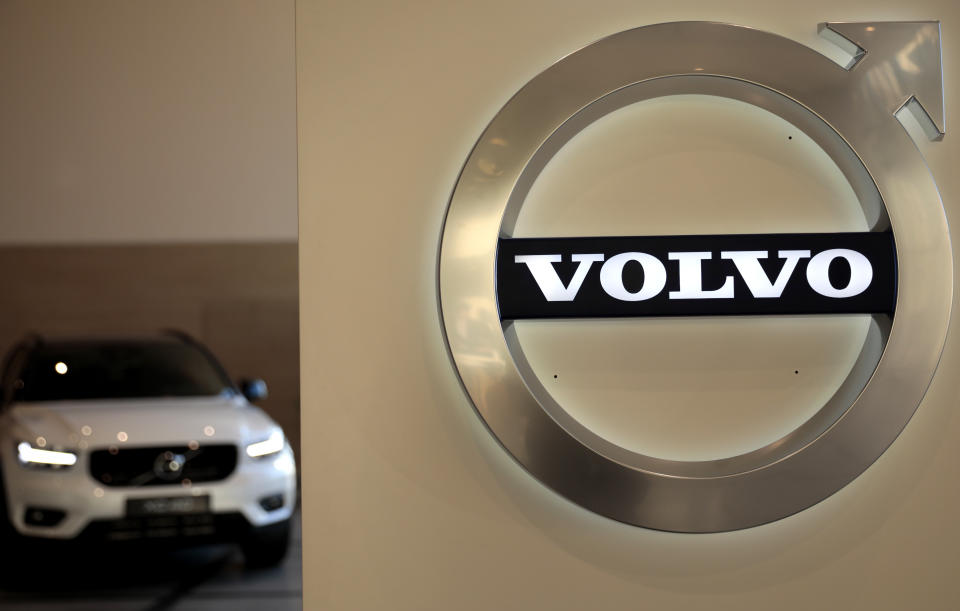 FILE - In this Feb. 6, 2020 file photo a Volvo car is parked behind the Volvo logo in the lobby of the company's corporate headquarters, in Brussels.  Volvo says it will make only electric vehicles by 2030. But for those who want one, they will have to buy it online.  The Swedish automaker said Tuesday, March 2, 2021,  that it is phasing out the production of all cars with internal combustion engines — including hybrids.  (AP Photo/Virginia Mayo, File)