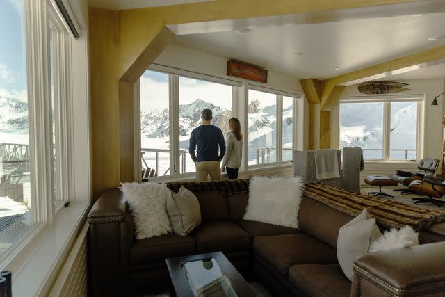 <p>Courtesy of Sheldon Chalet</p> A couple looking out at the snowy landscape at Sheldon Chalet in Alaska.