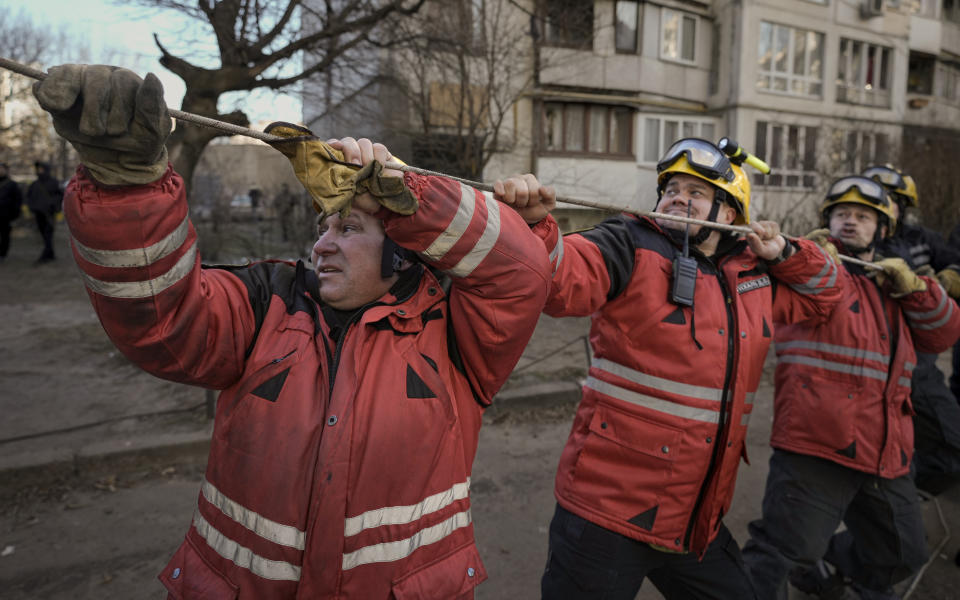 Firefighters pull a rope to direct the fall of a tree while working to extinguish a blaze in a destroyed apartment building after a bombing in a residential area in Kyiv, Ukraine, Tuesday, March 15, 2022. Russia's offensive in Ukraine has edged closer to central Kyiv with a series of strikes hitting a residential neighborhood as the leaders of three European Union member countries planned a visit to Ukraine's embattled capital. (AP Photo/Vadim Ghirda)