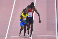 Braima Suncar Dabo of Guinea Bissau carries Jonathan Busby of Aruba to the finish line during the men's 5,000 meters heats during the World Athletics Championships Friday, Sept. 27, 2019, in Doha, Qatar. (AP Photo/Martin Meissner)