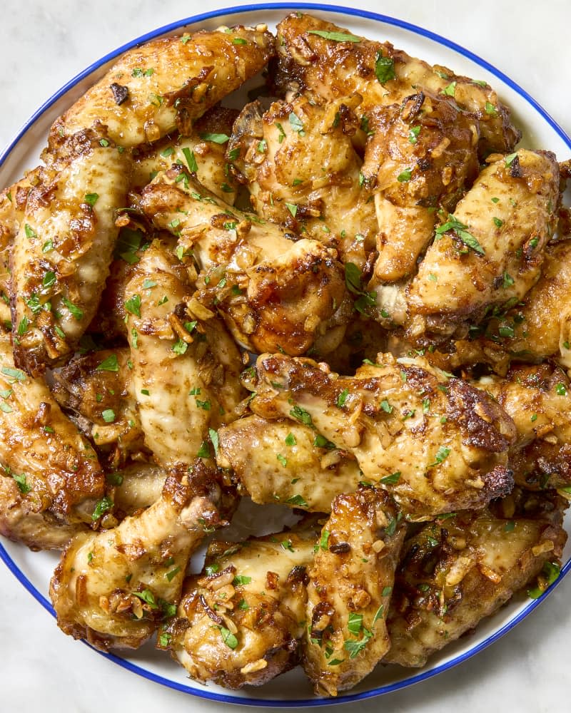 overhead shot of a large plate of french onion dip chicken wings, topped with herbs.