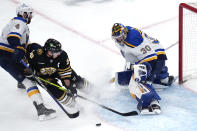 St. Louis Blues goaltender Joel Hofer (30) makes a save on a shot by Boston Bruins left wing Brad Marchand (63) during the first period of an NHL hockey game, Monday, March 11, 2024, in Boston. St. Louis Blues defenseman Nick Leddy, left, looks on. (AP Photo/Charles Krupa)