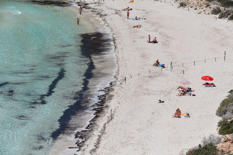 Beach goers enjoy the sun on a beach in the Island of Lampedusa, southern Italy, Friday, May 14, 2021. Lampedusa is closer to Africa than the Italian mainland, and it has long been the destination of choice for migrant smuggling operations leaving Libya. Over the years, it has witnessed countless numbers of shipwrecks and seen bodies floating offshore, only to be buried in the cemetery on land. (AP Photo/Salvatore Cavalli)