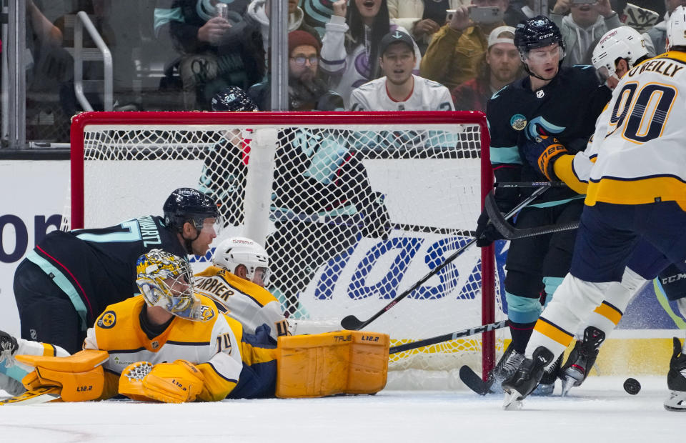 Seattle Kraken center Jaden Schwartz (17) collides with Nashville Predators goalie Juuse Saros and defenseman Alexandre Carrier, back center, after making a shot during the first period of an NHL hockey game Thursday, Nov. 2, 2023, in Seattle. (AP Photo/Lindsey Wasson)