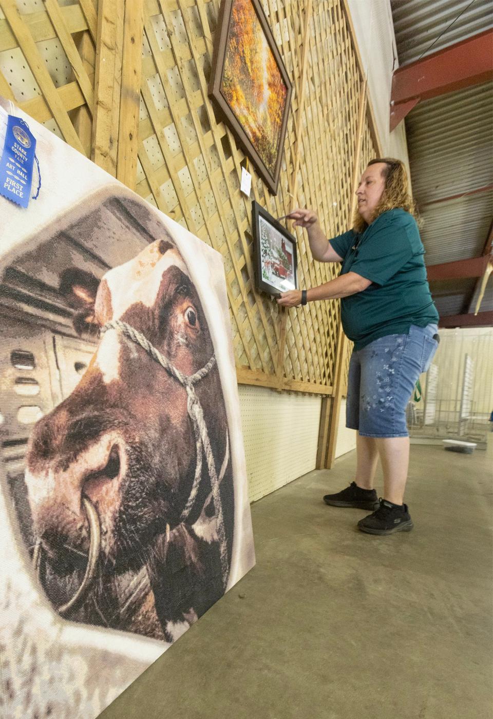 Jill Sterling, vice president of the senior fair board, arranges diamond dot art winners for display in the art hall at the Stark County Fair.