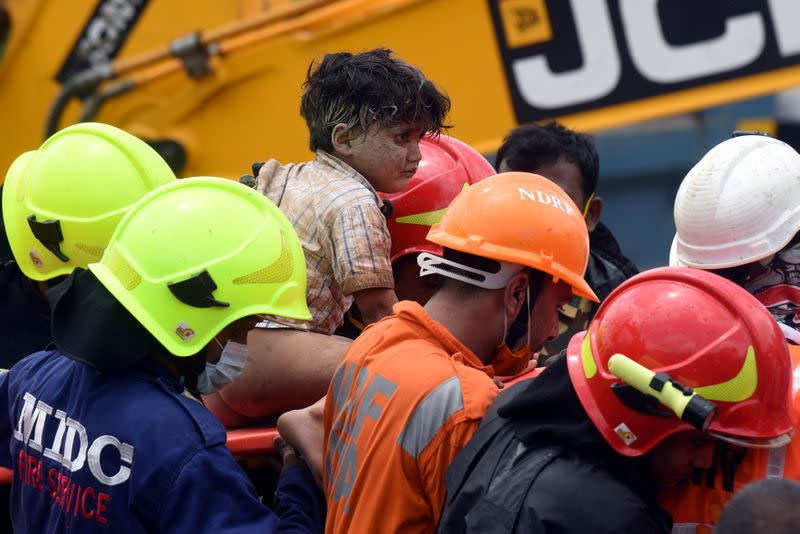 Rescue workers carry Mohammed Bangi after he was rescued from the rubble at the site of a collapsed five-storey building in Mahad