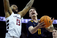 West Virginia forward Quinn Slazinski (11) looks to shoot under pressure from Cincinnati forward Jamille Reynolds (13) during the first half of an NCAA college basketball game Tuesday, March 12, 2024, in Kansas City, Mo. (AP Photo/Charlie Riedel)