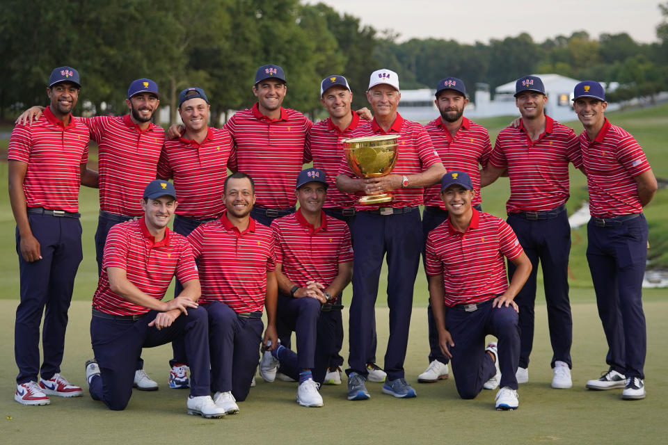 USA team captain Davis Love III, white hat, and his team pose for a photo with the Presidents Cup trophy after defeating the International team in match play at the Presidents Cup golf tournament at the Quail Hollow Club, Sunday, Sept. 25, 2022, in Charlotte, N.C.(AP Photo/Julio Cortez)