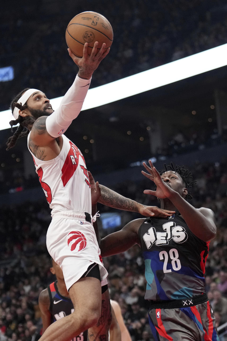 Toronto Raptors guard Gary Trent Jr. (33) drives to the net over Brooklyn Nets forward Dorian Finney-Smith (28) during the first half of an NBA basketball game in Toronto, Monday, March 25, 2024. (Nathan Denette/The Canadian Press via AP)