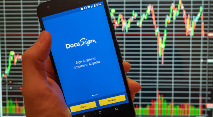 Docusign (DOCU) logo on a phone screen with stock charts in background