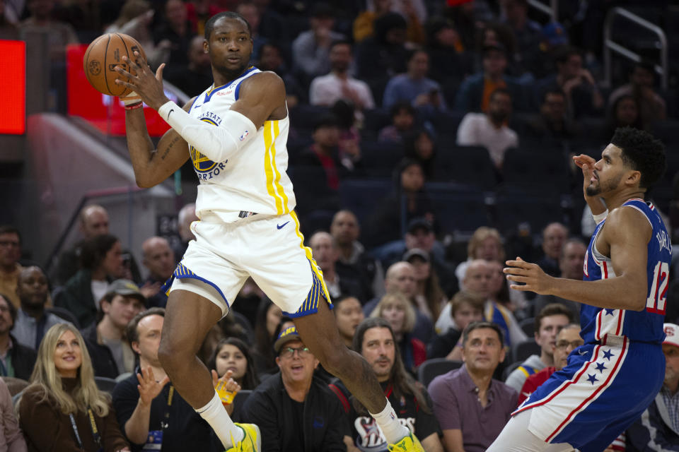 Golden State Warriors forward Jonathan Kuminga, left, passes away from defensive pressure by Philadelphia 76ers forward Tobias Harris (12) during the first half of an NBA basketball game, Tuesday, Jan. 30, 2024, in San Francisco. (AP Photo/D. Ross Cameron)