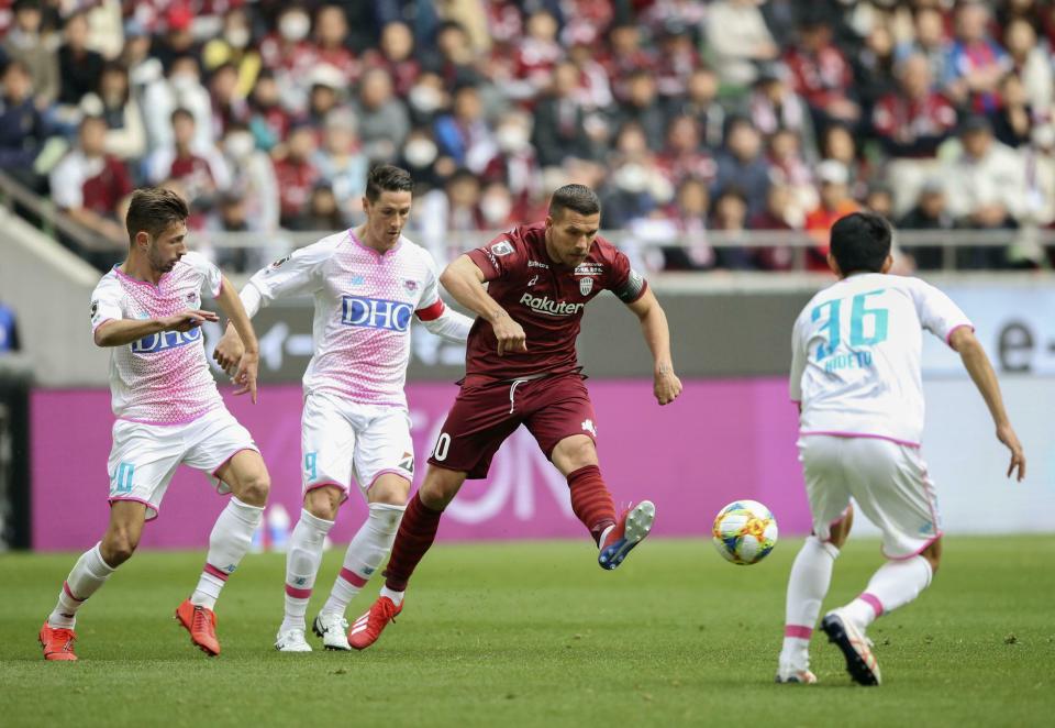 Vissel Kobe's Lukas Podolski, center, controls the ball against Sagan Tosu's Fernando Torres, center left, during a J-League soccer match in Kobe, western Japan, Saturday, March 2, 2019.(Kyodo News via AP)