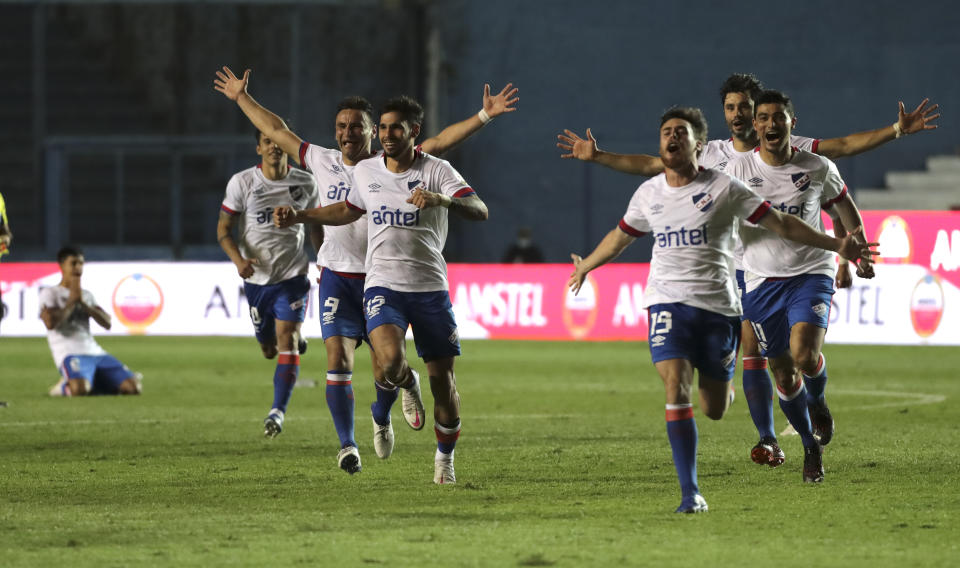 Los jugadores del Nacional de Uruguay corren hacia su compañero Emiliano Martínez para celebrar su gol de la victoria contra Independiente del Valle de Ecuador en la tanda de panales 4-2 para avanzar a los cuartos de final de la Copa Libertadores en Montevideo, Uruguay, el miércoles 2 de diciembre de 2020 (Raúl Martínez/Pool vía AP).