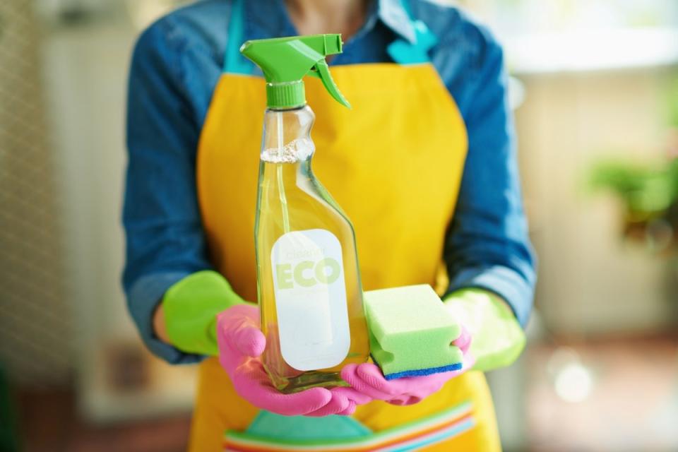 Woman in yellow apron holding eco-friendly cleaning product