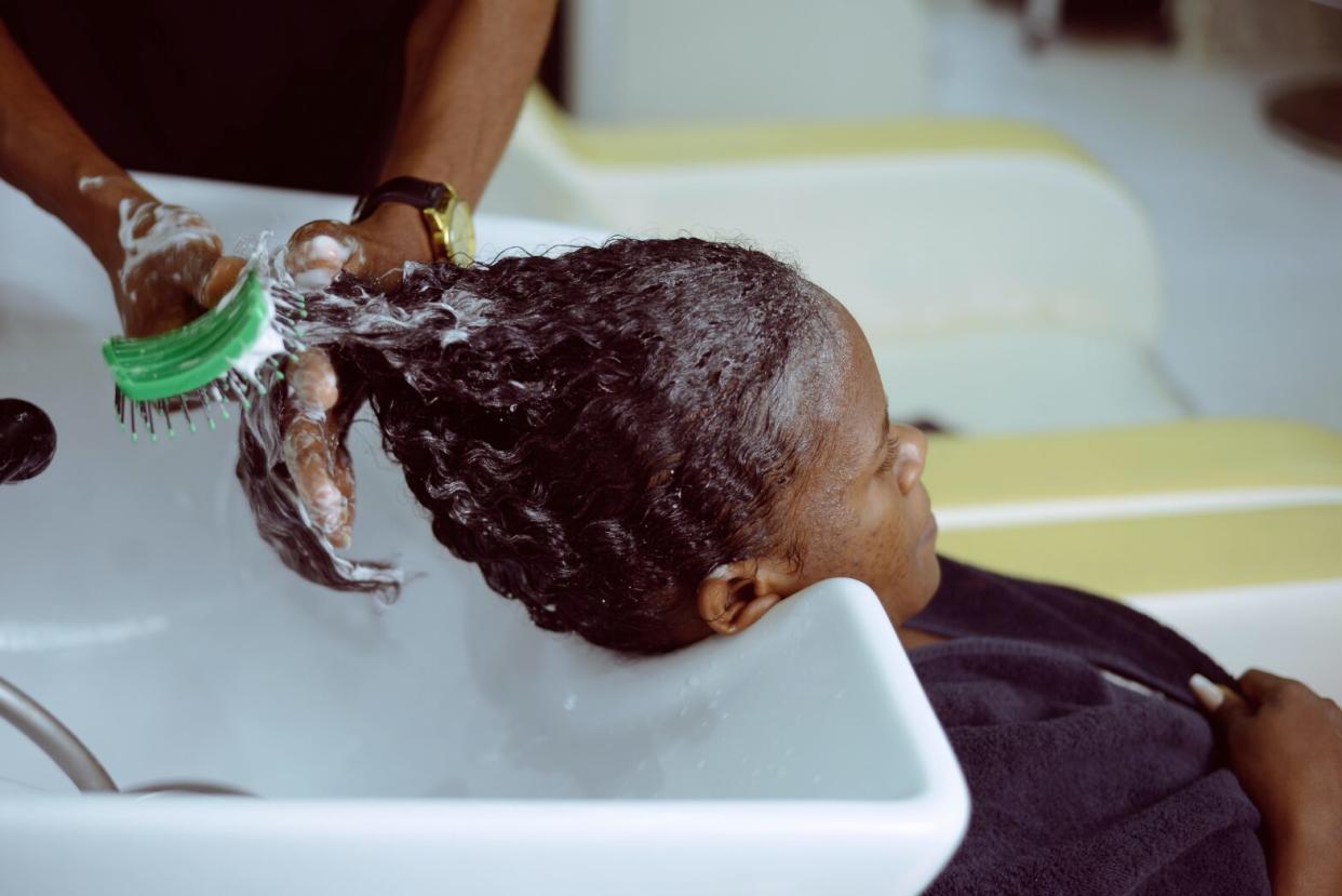 Black woman in hair salon getting hair brushed in sink