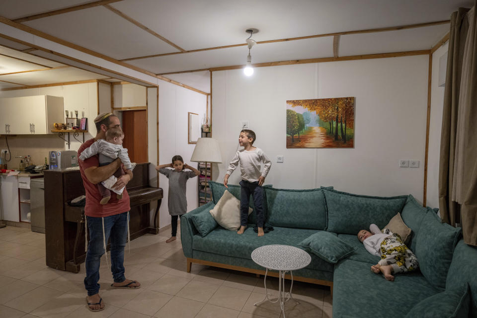 The Grenshpan family gathers in the living room of their trailer in the early morning at the Jewish outpost of Beit Hogla, in the West Bank, Thursday, Feb. 16, 2023. Israel's new ultranationalist government declared last week that it would legalize 10 unauthorized outposts in the occupied West Bank. The rare move intensified the country's defiance of international pressure and opened an aggressive new front of Israeli expansion into the West Bank, which Israel captured in the 1967 Mideast war. (AP Photo/Ohad Zwigenberg)