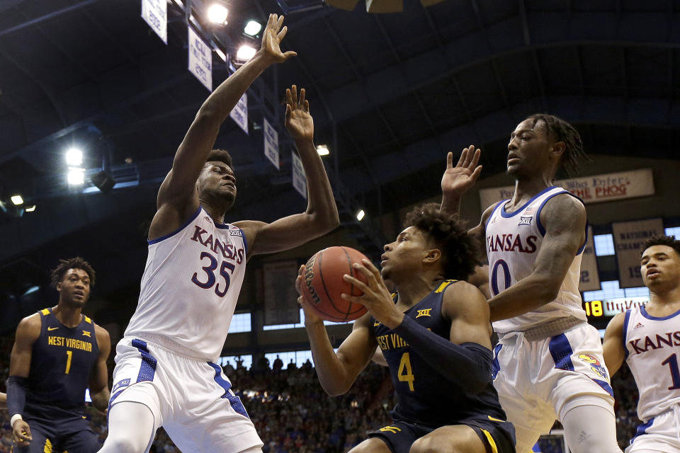 West Virginia's Miles McBride (4) looks to shoot under pressure from Kansas' Udoka Azubuike (35) and Marcus Garrett (0) during the second half of an NCAA college basketball game Saturday, Jan. 4, 2020, in Lawrence, Kan. (AP Photo/Charlie Riedel)