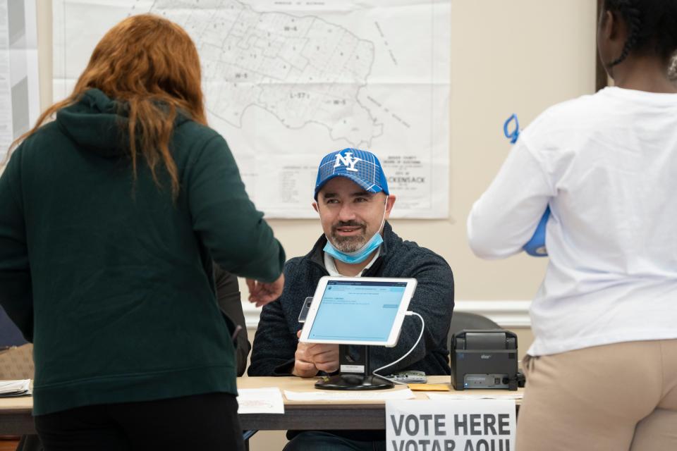 James Johnson, a poll worker, signs in a voter before she casts her ballot at the Civic Center in Hackensack, N.J. on Tuesday Nov. 8, 2022. 