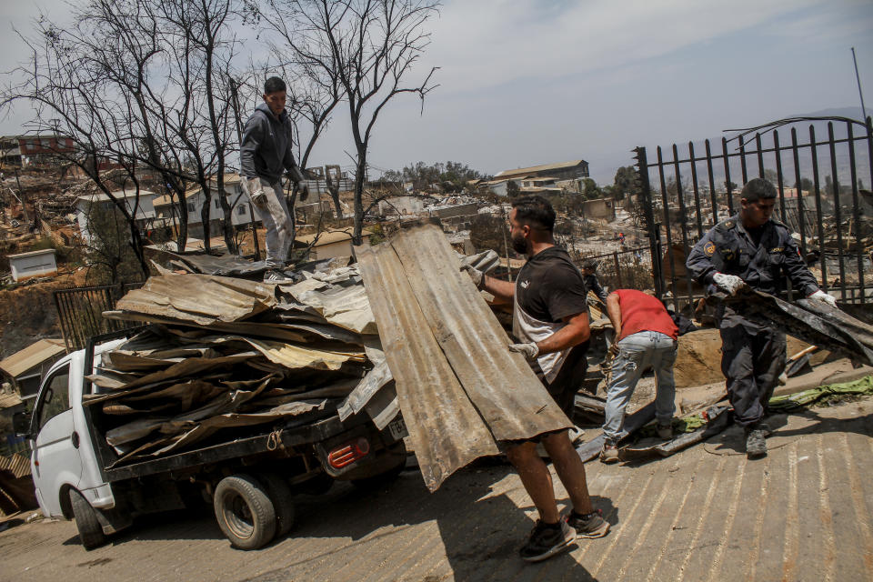 Locals clean the rubble of burnt-out houses after forest fires reached their neighborhood in Vina del Mar, Chile, Sunday, Feb. 4, 2024. (AP Photo/Cristobal Basaure)