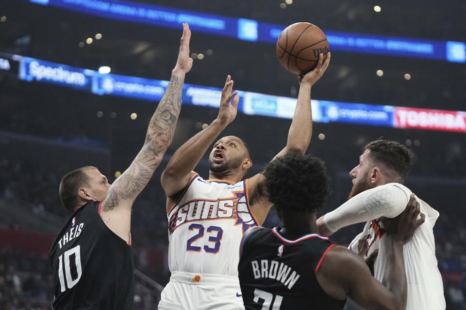 Phoenix Suns guard Eric Gordon, second from left, shoots as Los Angeles Clippers center Daniel Theis, left, defends, while Clippers guard Kobe Brown, second from right, and Suns center Jusuf Nurkic battle for position during the first half of an NBA basketball game Wednesday, April 10, 2024, in Los Angeles. (AP Photo/Mark J. Terrill)