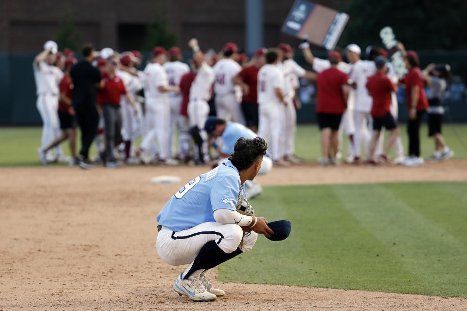 North Carolina's Johnny Castagnozzi (19) reacts as Arkansas celebrates in the background following an NCAA college super regional baseball game in Chapel Hill, N.C., Sunday, June 12, 2022. (AP Photo/Karl B DeBlaker)