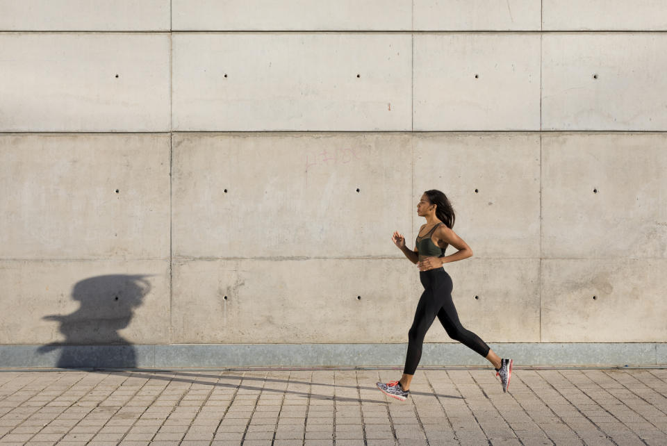 Young woman running along concrete wall in the city