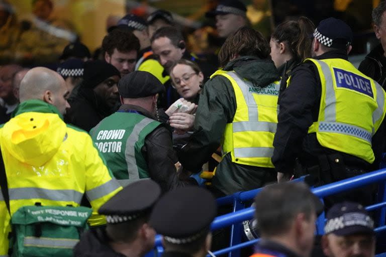 Los equipos médicos se llevan a un aficionado de Leeds después de caer desde la parte superior celebrando su primer gol durante el partido de fútbol de quinta ronda de la Copa FA inglesa entre Chelsea y Leeds United en Stamford Bridge, en Londres