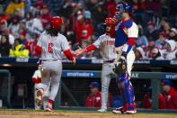 Cincinnati Reds' Nick Martini, center, celebrates with Jonathan India, left, after they scored on a double by Christian Encarnacion-Strand against the Philadelphia Phillies during the third inning of a baseball game, Wednesday, April 3, 2024, in Philadelphia. (AP Photo/Chris Szagola)