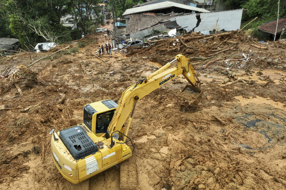 A machine removes mud after a deadly mudslide triggered by heavy rains covered homes near Juquehy beach in the coastal city of Sao Sebastiao, Brazil, Monday, Feb. 20, 2023. (AP Photo/Andre Penner)