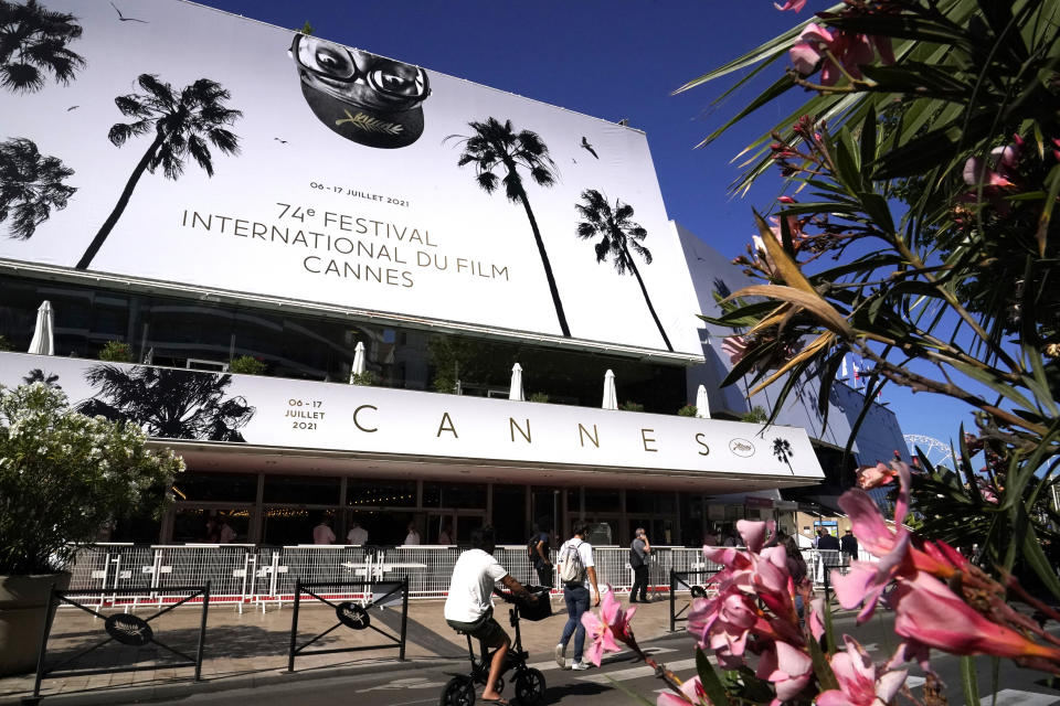 Members of the public walk in front of the Palais des Festival prior to the 74th international film festival, Cannes, southern France, July 5, 2021. The Cannes film festival runs from July 6 - July 17, 2021. (AP Photo/ Brynn Anderson)