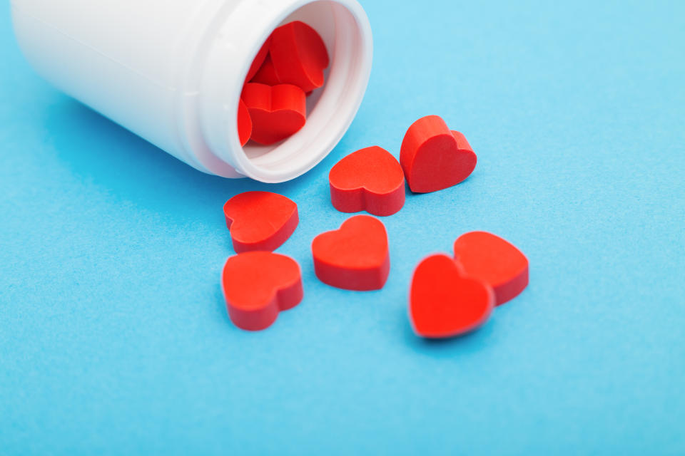 Humans can be addicted to anything that releases dopamine, including the feeling of falling in love. (Getty) Red heart shaped pills with plastic bottle on blue background.Concept love addiction, love drugs, Valentine's Day and depression