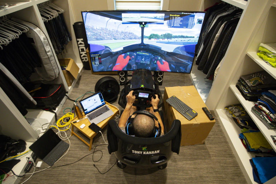 IndyCar driver Tony Kanaan, of Brazil, practices on his racing simulator in his home in Indianapolis, Saturday, March 28, 2020. Kanaan, along with other IndyCar drivers and NASCAR's Jimmie Johnson will compete in the series' inaugural virtual racing event Saturday. (AP Photo/Michael Conroy)