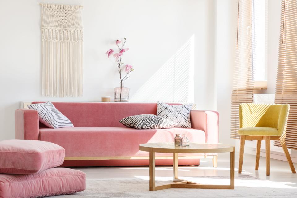 pink couch on white wall with round table in front 