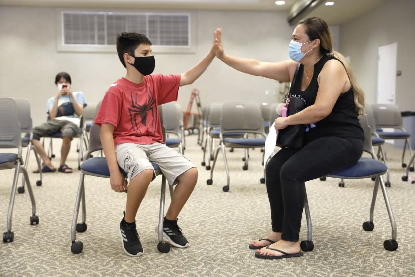 TORRANCE-CA-JULY 7, 2021: Zuly Gomez, 42, right, congratulates her son Dean, 13, left, after receiving his first dose of the Pfizer vaccine at El Camino College in Torrance on Wednesday, July 7, 2021 as the college hosts a one-day COVID-19 vaccination clinic on campus, run by Providence, open to the public for individuals aged 12 and up. In anticipation of her son's in person school year coming up, Gomez said, "It's better safe than sorry. I just feel strongly about the science and I just think it's better this way." (Christina House / Los Angeles Times)