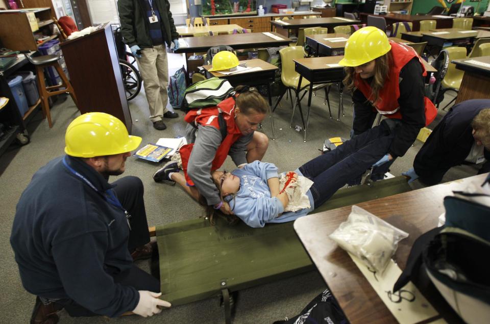 Bella BeSerra, 9, role-plays the part of an injured student as she is lifted by P.E. teacher Kelly Miller, second from left, and health care assistant Piper Marker, right, onto a gurney as teacher Phil Schmitt looks on at left, during an earthquake drill at Twin Lakes Elementary School in Federal Way, Wash., Thursday, Oct. 18, 2012. Millions of people took part in the “Great Shakeout” earthquake drill across the country and elsewhere Thursday to practice and prepare for the possibility of real quakes in the future. (AP Photo/Ted S. Warren)