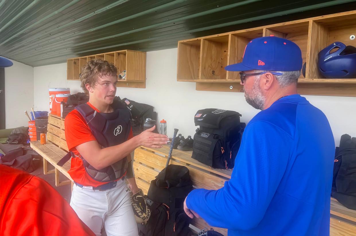 Olentangy Orange pitching coach Zane Bayliss and catcher Casey Covert discuss strategy during an OCC-Central contest April 9 at Dublin Coffman. Orange is using the CoachComm communication system during games this season.