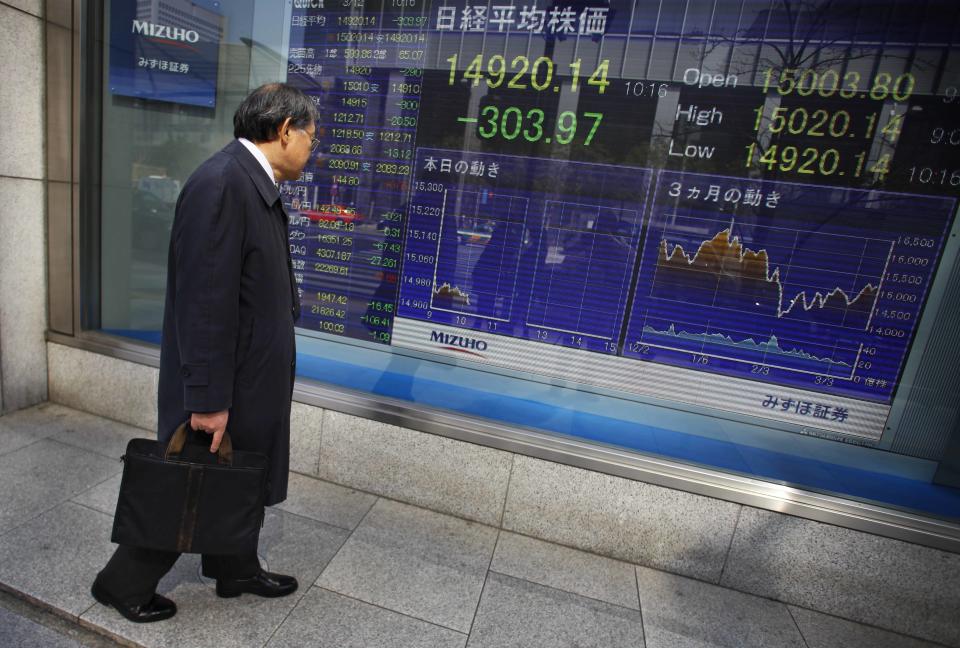 A man stops and looks at Japan's Nikkei stock update on an electric board at a securities firm in Tokyo, Wednesday, March 12, 2014. Asian stock markets sank Wednesday as recent falls in Chinese copper and iron prices added to jitters that the world's No. 2 economy is continuing to slow. (AP Photo/Junji Kurokawa)