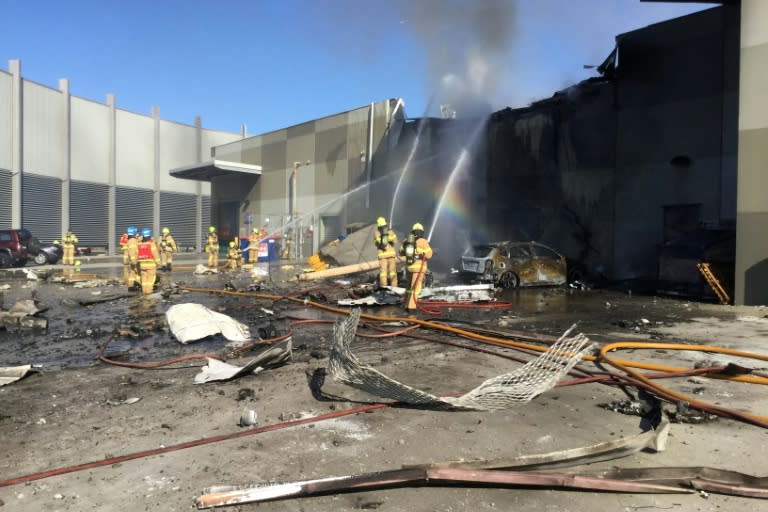 Firemen put out a blaze from a light aircraft which exploded as it smashed into a shopping centre near Melbourne on February 21, 2017 killing five people aboard