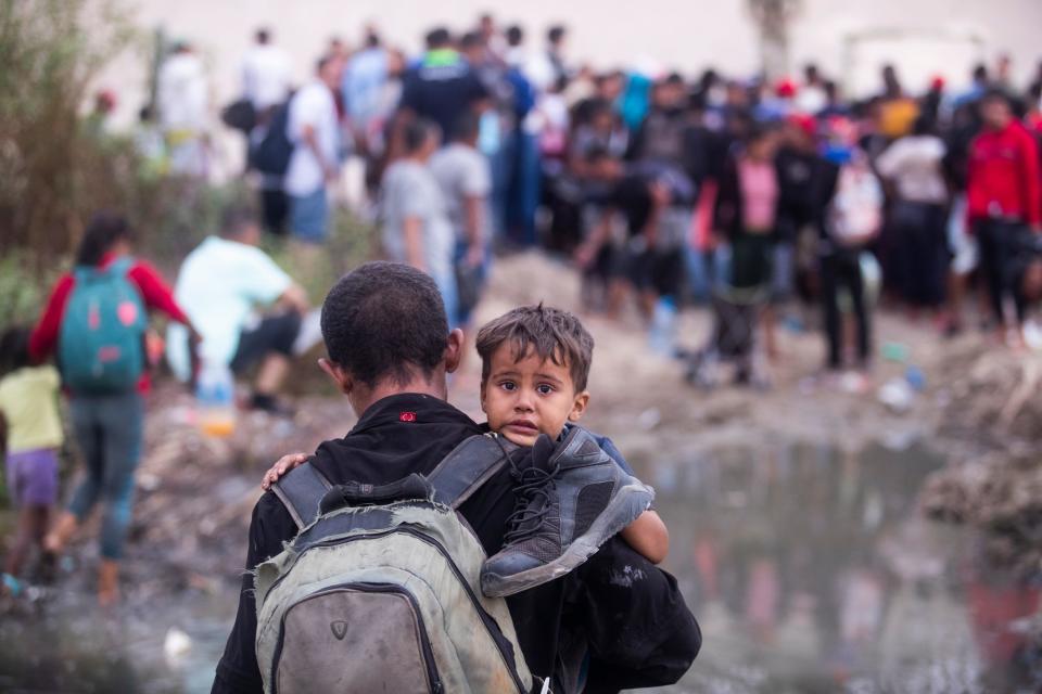 A migrant father and his son cross the Rio Grande to see if the Texas National Guard would allow them to turn themselves to U.S. Border Patrol on Sept. 12, 2023.